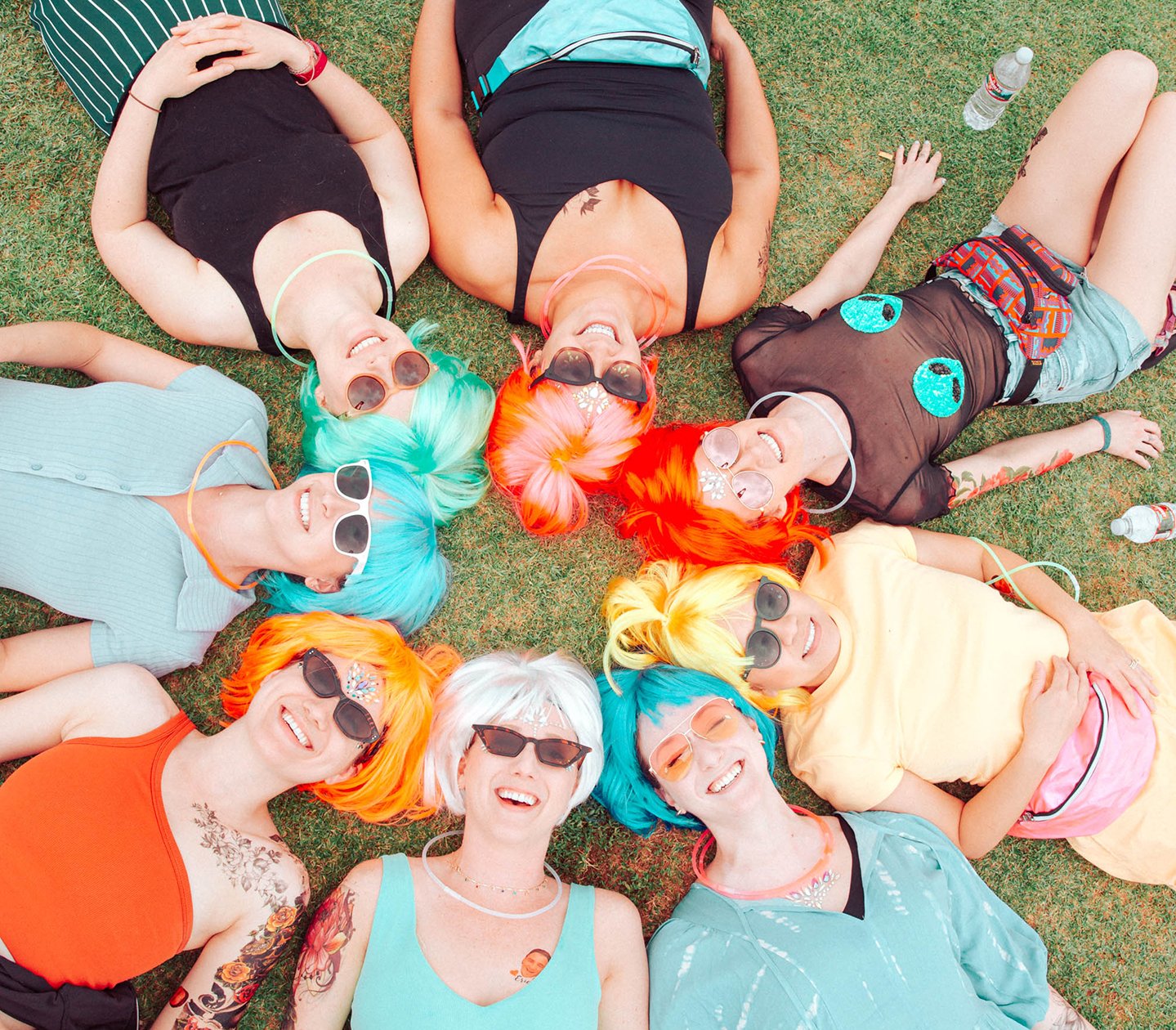 Friends lying together in a circle on the grass at a festival.